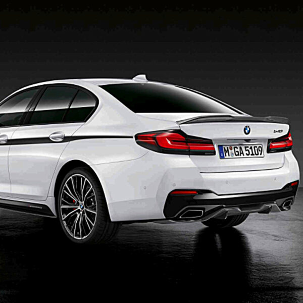 Eine weiße BMW-Limousine ist von hinten vor einem dunklen Hintergrund