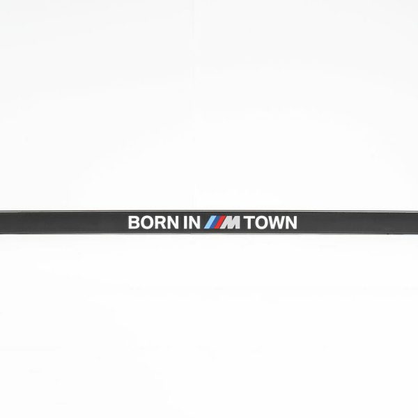 Der "kennzeichenhalter born in m town 3" ist ein schwarzer BMW Kennzeichenhalter mit dem Text BORN IN M TOWN, mit dem M in blauen, lila und roten BMW M Streifen, dargestellt auf einem schlichten weißen Hintergrund.
